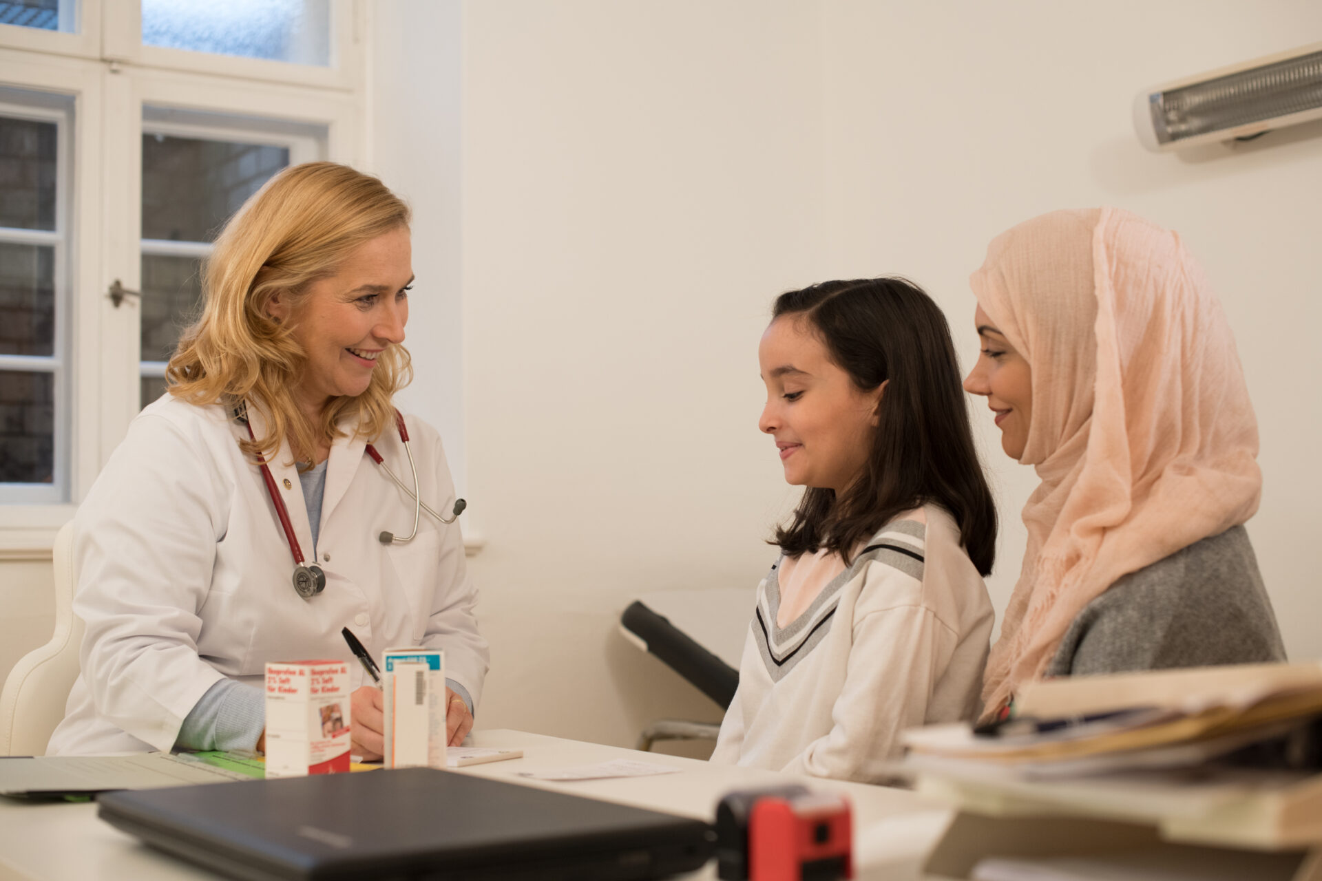 A physician consults with two women an a medical office.
